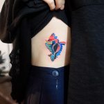 Abstract colorful tattoo on the ribcage