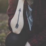Black arrow tattoo on the right forearm