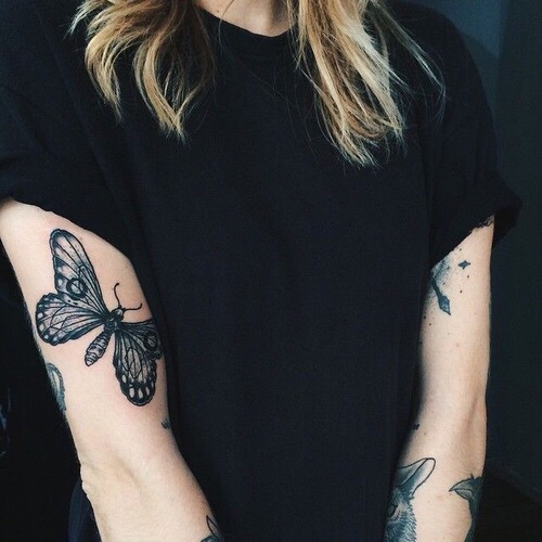 Black butterfly tattoo on the right upper arm 