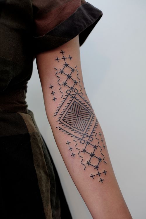 Black geometric tattoo on the left arm