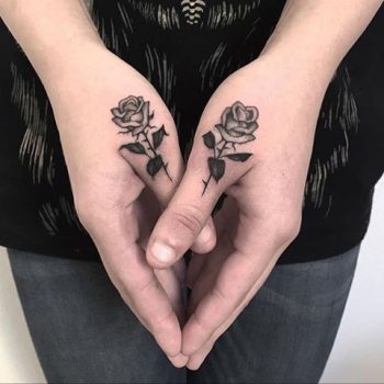Black rose tattoos on thumbs
