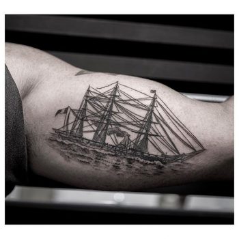 Black ship tattoo on the bicep