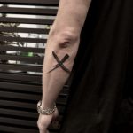 Brush paint mark x tattoo on the forearm