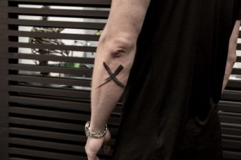 Brush paint mark x tattoo on the forearm