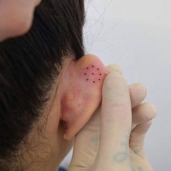 Circled dot tattoo on ear