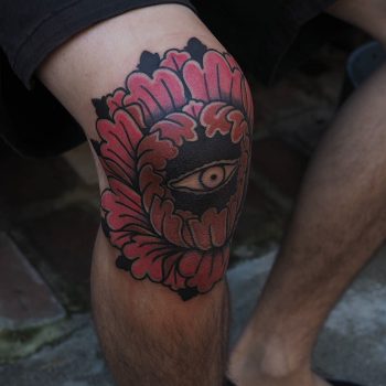 Flower and eye tattoo on the knee