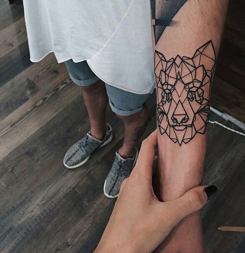 Geometric wolf head tattoo on the inner arm