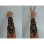 Large black mandala tattoo on the arm
