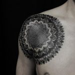 Large black mandala tattoo on the chest and shoulder