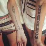 Matching arrow tattoos on arms