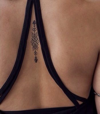 Minimal geometric arrow tattoo on the center of the back