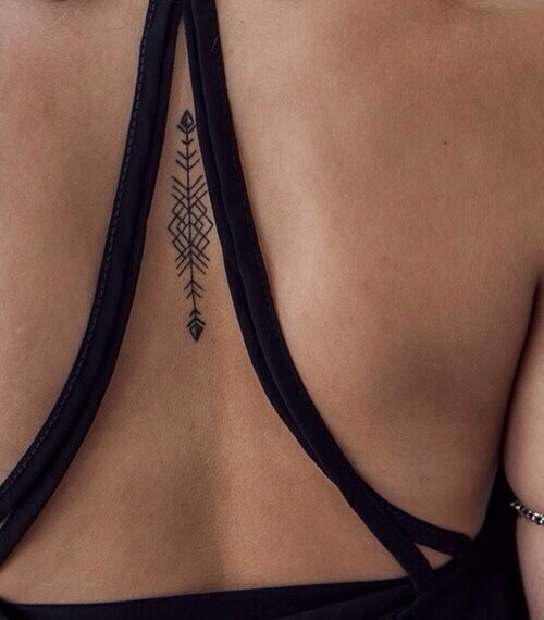 Minimal geometric arrow tattoo on the center of the back