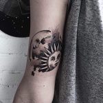 Moon and sun circular tattoo on the inner arm