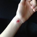 Red paper crane tattoo on the wrist