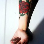 Red rose tattoo with green leaves