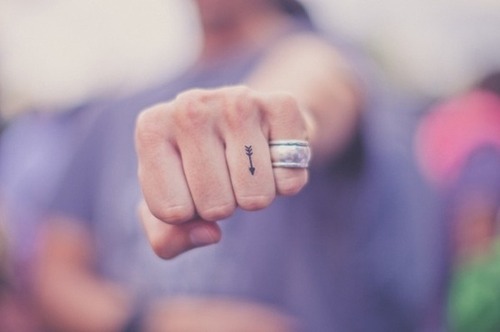 Tiny arrow tattoo on the ring finger