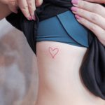 Tiny red heart tattoo on the rib cage