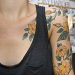 Yellow flower tattoo on the shoulder and sleeve