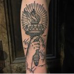 A hand holding a torch tattoo