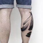 Abstract black paint brush tattoo on the calf