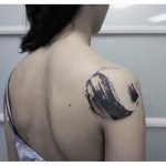 Abstract black tattoo on the right shoulder blade