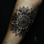 Black mandala tattoo on the left forearm