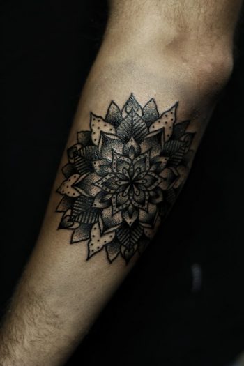 Black mandala tattoo on the left forearm