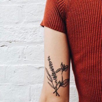 Black minimal flower tattoo on the inner arm