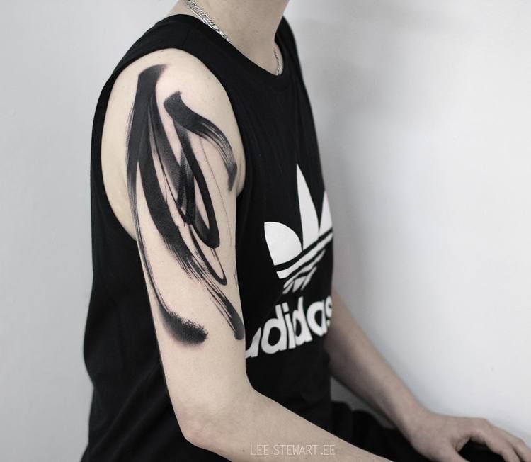 Black paintbrush tattoo on the arm