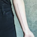Black thin long line tattoo on the arm