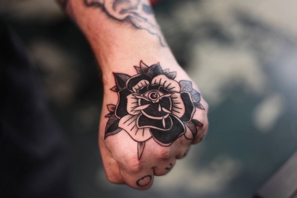 Black traditional rose tattoo on the hand