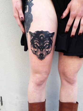 Black wolf head tattoo on the right thigh
