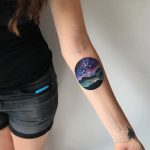 Circular landscape tattoo on the arm