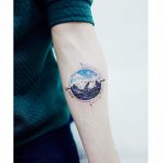Circular mountain landscape tattoo and a compass