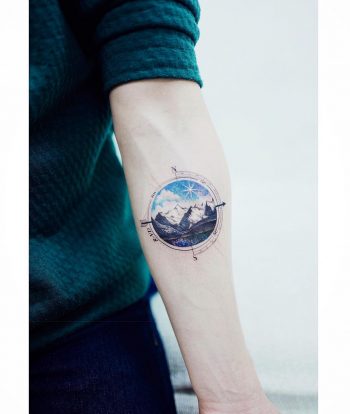 Circular mountain landscape tattoo and a compass