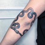 Circular snake tattoo around the elbow