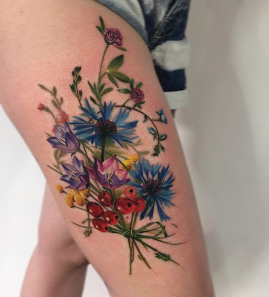 Colorful wildflowers tattoo on the thigh