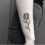 Delicate black rose tattoo on the forearm