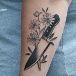 Knife and flowers tattoo on the forearm