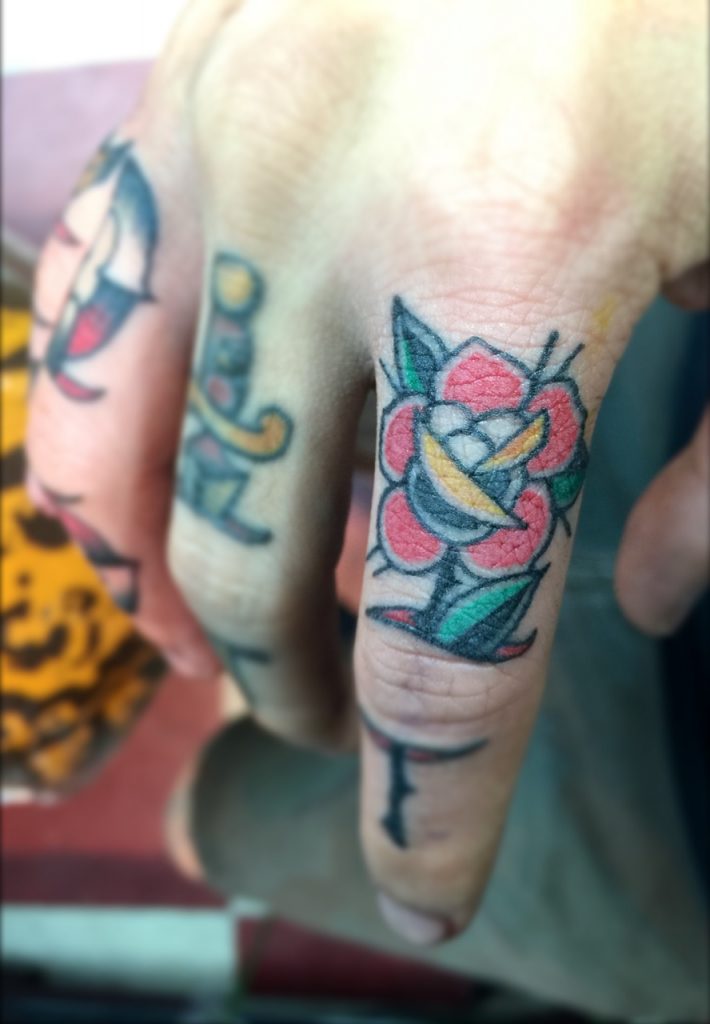 Rose stabbed finger tattoo