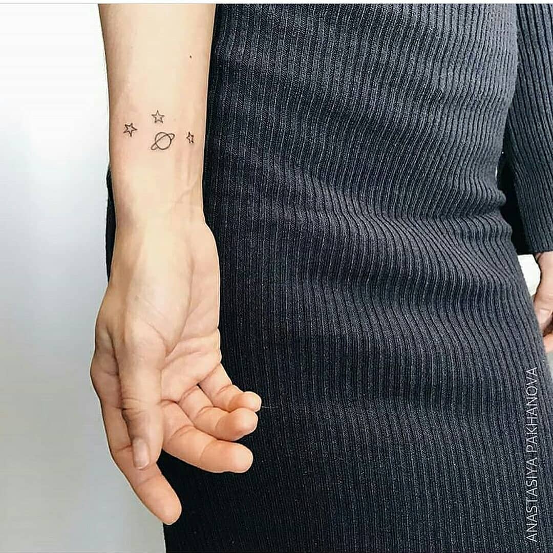 Saturn and stars tattoo on the wrist