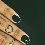 Small black heart tattoo on the ring finger