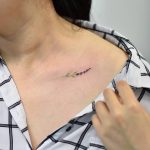 Small delicate flower tattoo on the clavicle bone