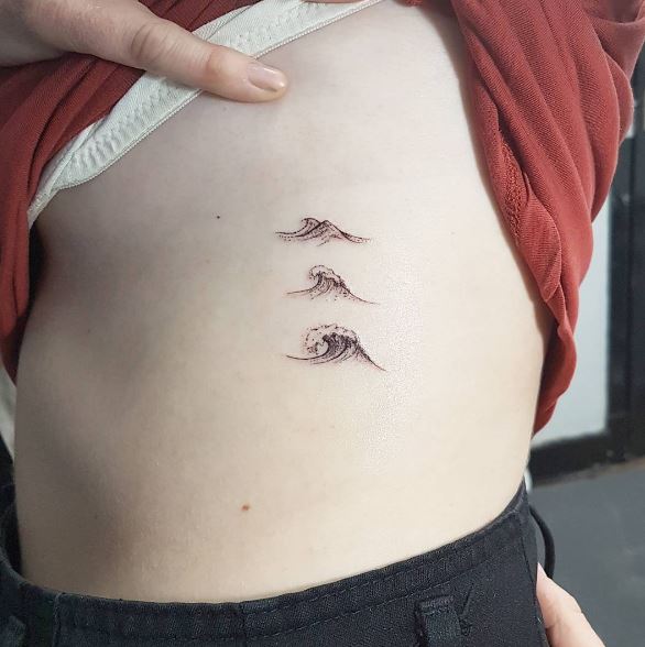 Small wave tattoo on the rib cage