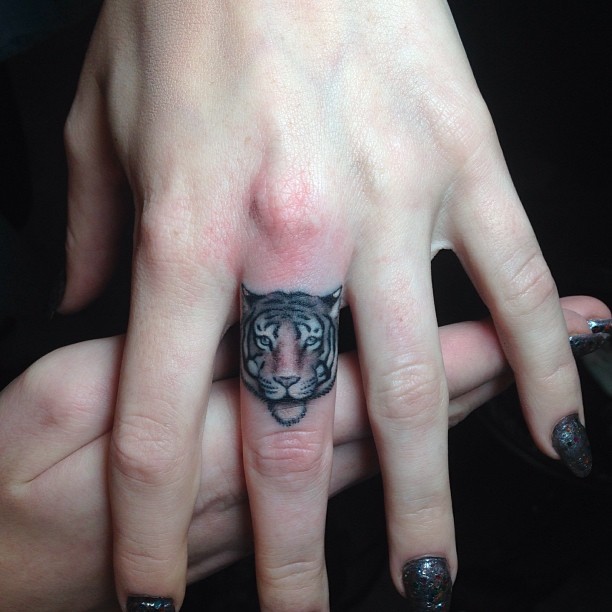 Tiger head tattoo on the middle finger