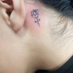 Tiny black rose tattoo behind the ear