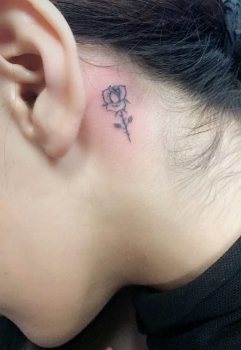 Tiny black rose tattoo behind the ear