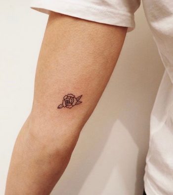 Tiny black rose tattoo on the inner arm