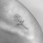 Tiny black rose tattoo on the shoulder