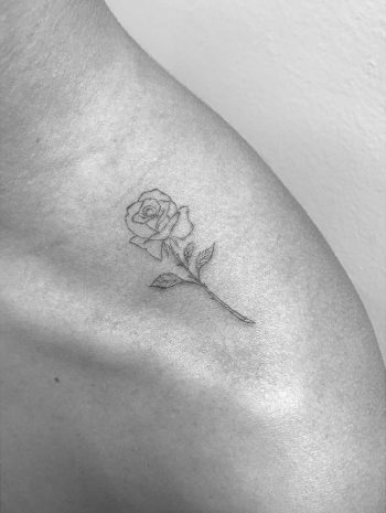 Tiny black rose tattoo on the shoulder